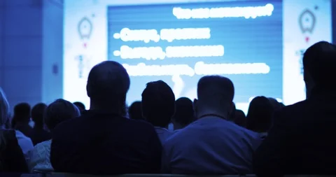 Viewers looking at presentation on screen and listening man speaker on stage. Stock Footage 120294339