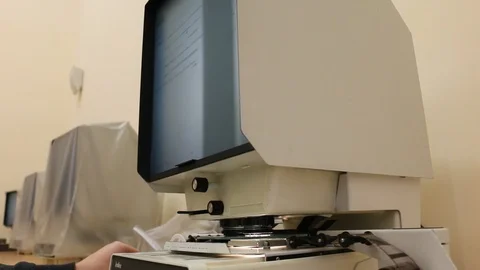 Viewing document slides on microfilm device display 스톡 동영상 99160060