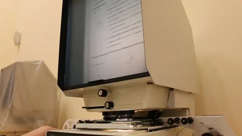 Viewing document slides on microfilm device display 스톡 동영상 99160117