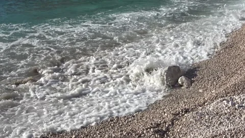 Viewing sea waves washing over white pebbles Видео 332861033