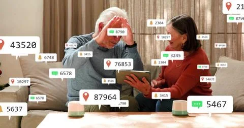 Viewing senior couple in gray, rust sweaters reacting on sofa at home, showing Stock Photos