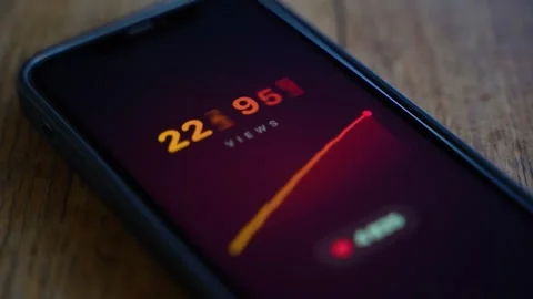 Views counter with rising graph on smartphone screen lying on wooden table 库存影片 343237535