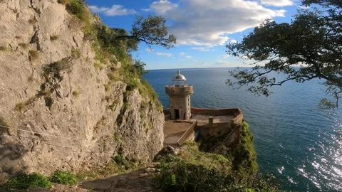 Views of a lighthouse located in a beautiful setting of cliffs by the sea in Video stock 141808676
