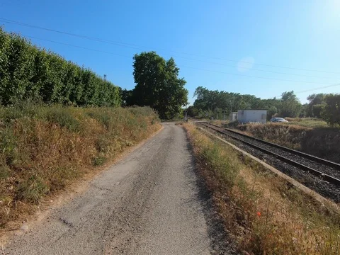 Views of a road next to train tracks on a sunny day with clouds. Видео 108214629