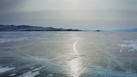 Vigorous flight over the bare ice of Lake Baikal, solar reflection on the Stock Footage 228826665