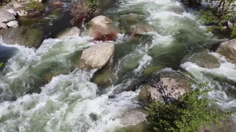 The vigorous flow of a river snakes its way around boulders and rocks Stock Footage 253542335