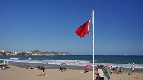 Villa Joyosa beach with red warning flag fluttering in the wind Видео 284012926