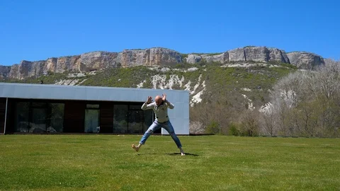 Villa in the mountains. Middle-aged man doing workout on the grass. Capoeirajump Stock Footage 129731553