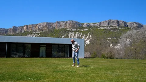 Villa in the mountains. Middle-aged man doing workout on the grass. Capoeirajump 스톡 동영상 129731603