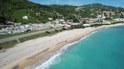 Village along a curving beach beneath wind turbines, aerial view Stockbeeldmateriaal 278369953