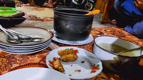 A village meal with shared tableware, featuring abundant rice and plates. Stock Photos
