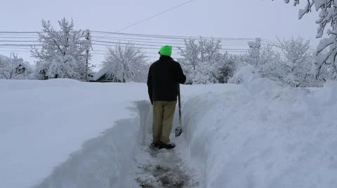 A villager clears a path to the front yard after a snow storm Photos