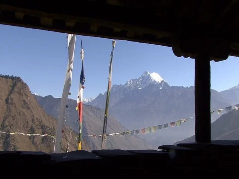 Villager wal past prayer flags with Himalayas in background Stock Footage 86748830