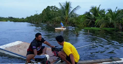 Villagers testing improvised foam board motorboats during rural flood disaster 動画素材 348892161