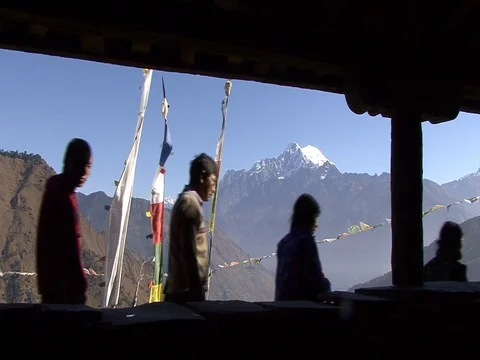 Villagers walk past prayer flags with Himalayas in background Stock Footage 86748828