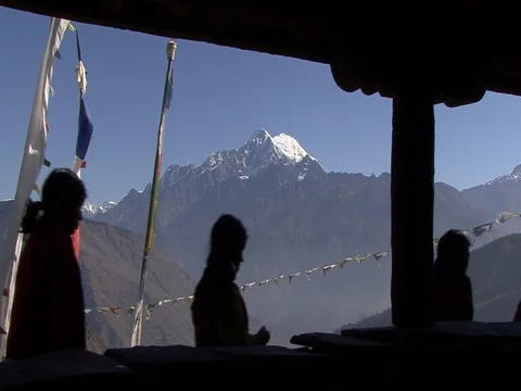 Villagers walk past prayer flags with Himalayas in background Stock Footage 86748840