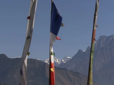 Villagers walk past prayer flags with Himalayas in background Stock Footage 86748847