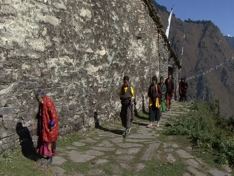 Villagers walking on mountain path past stone temple. Stock Footage 86748850