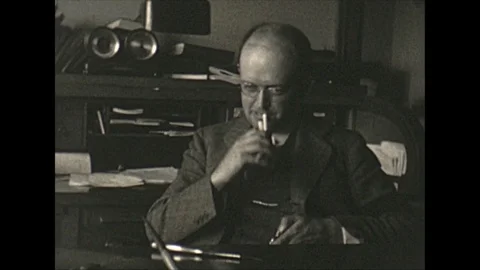 Vintage 16mm film, 1928 Pennsylvania, man at desk lights up cigarette Stock Footage