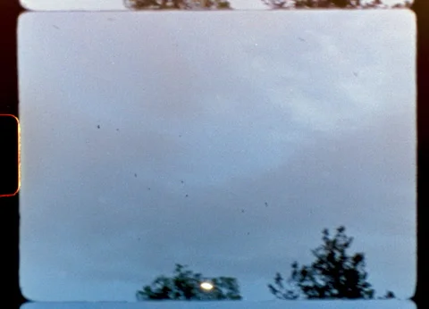 Vintage 8mm camera capturing flock of birds flying in cloudy sky Stock Footage 306685901