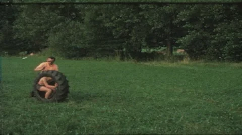 Vintage 8mm film: Boy in tire rolled by father, 1970s Stock Footage