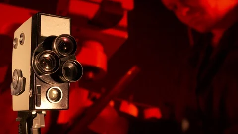 Vintage 8mm film camera in front of flickering old movie background Stock Footage 100711061