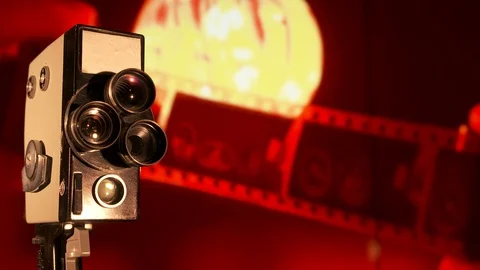 Vintage 8mm film camera in front of flickering old movie background Stock Footage 100711083