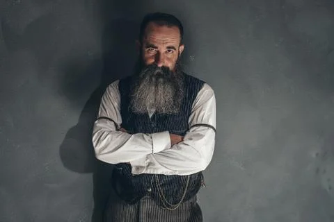 Vintage beard man in 1900 style fashion against grey wall. Stock Photos