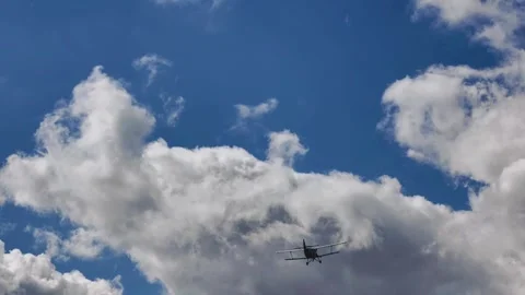 Vintage Biplane Soaring Through Blue Sky With Dramatic Clouds Stock Footage 345064347