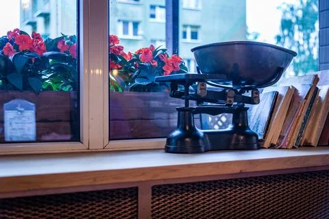 Vintage Black Kitchen Scale on Windowsill With Flowers and Books Stock Photos