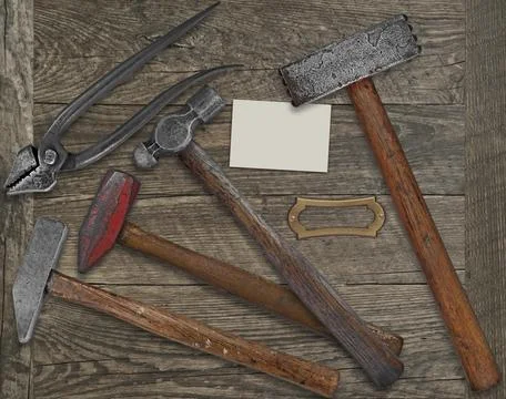 Vintage blacksmith or metalwork tools over wooden bench, blank plate and Stock Photos