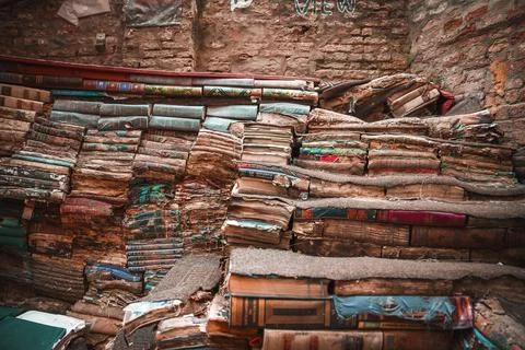 Vintage books in disarray in dimly lit, cozy room with warm sunlight streaming Stock Photos
