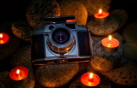Vintage Camera placed between burning candles on stones - nostelgic theme Stock Photos