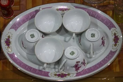 Vintage ceramic teacups with floral patterns arranged on porcelain serving tr Stock Photos