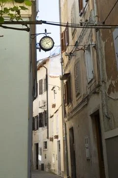 A vintage clock hangs above a narrow street in Piran, Slovenia Fotos Stock