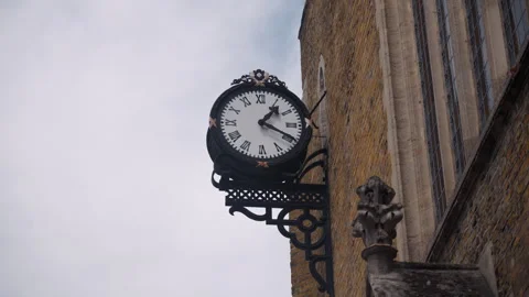 Vintage clock hangs on the wall of a brick house outside. Retro clock runs and Stock Footage 295055831