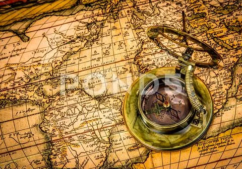 Vintage compass lies on an ancient world map. Stock Photos