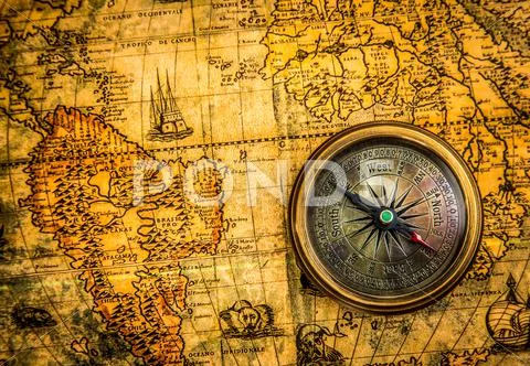 Vintage compass lies on an ancient world map Stock Photos