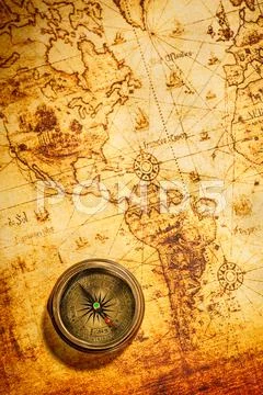 Vintage compass lies on an ancient world map. Stock Photos