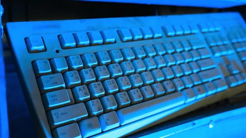 Vintage computer keyboard lit in blue neon light Stock Footage 347280403
