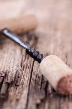 Vintage corkscrew and wine cork on wooden surface macro closeup Stock Photos