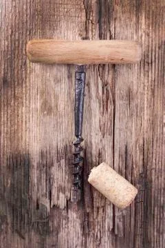 Vintage corkscrew and wine cork on wooden surface macro closeup Stock Photos