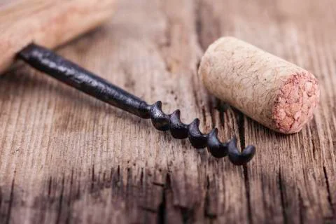 Vintage corkscrew and wine cork on wooden surface macro closeup Stock Photos