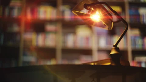 Vintage desk lamp glows in library with bookshelves in background, reading hobby Stock Footage 342731783