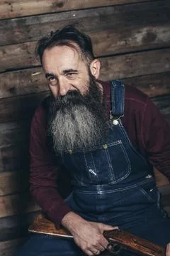 Vintage farmer holding rifle sitting on wooden crate in barn. Foto stock