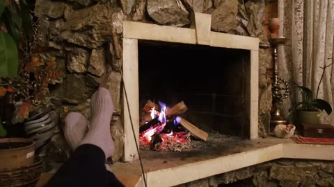 Vintage fireplace. General plan of a retro wood burning stove. Feet in socks are Stock Footage 302354070