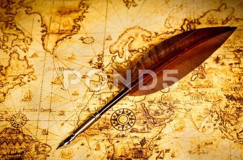 Vintage goose quill pen lying on an old map. Stock Photos