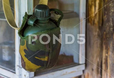 Vintage green drinking flask in a military printed bag, basic survival equipm Stock Photos