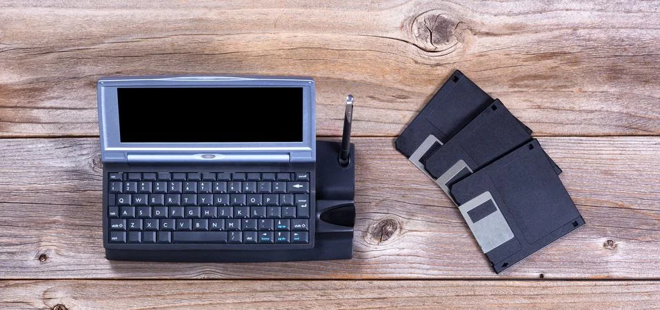Vintage handheld computer and data disks on rustic wooden boards Foto stock