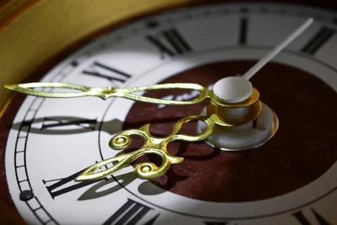 Vintage hands of old golden clock casting shadow on dial with Roman numeral Stock Photos
